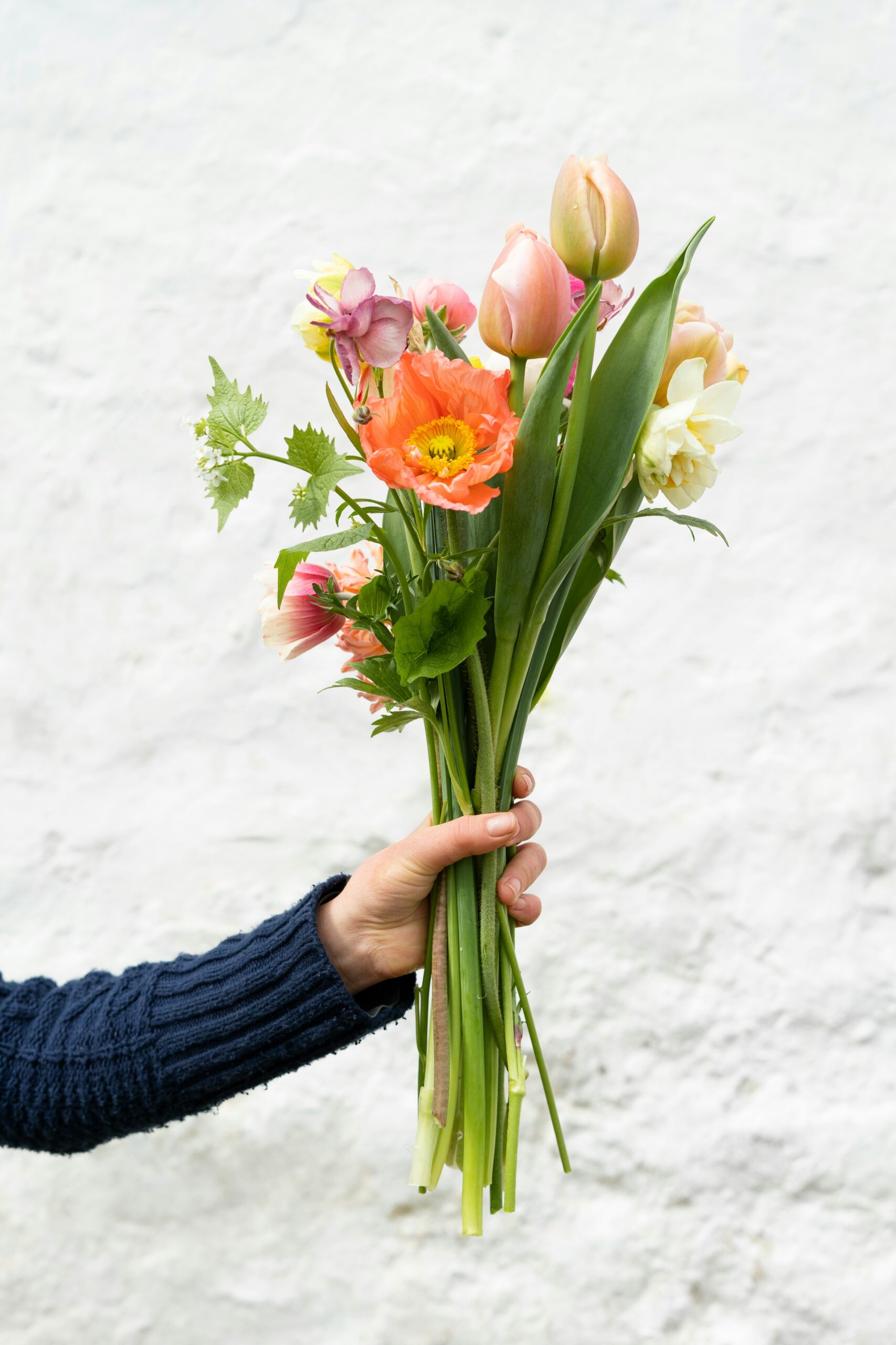 a hand holding a bouquet of spring flowers